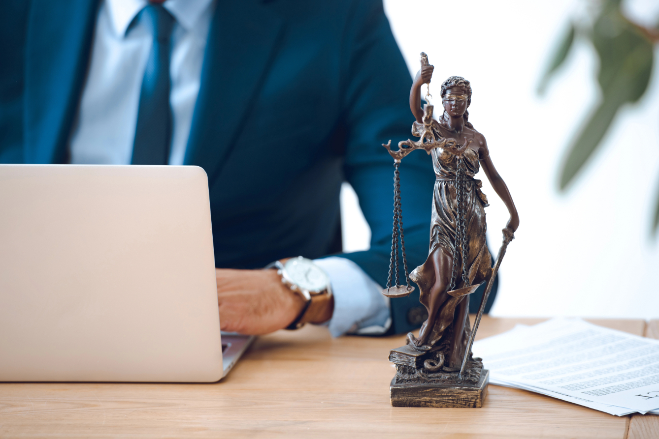 Lady Of Justice statue next to lawyer working on laptop